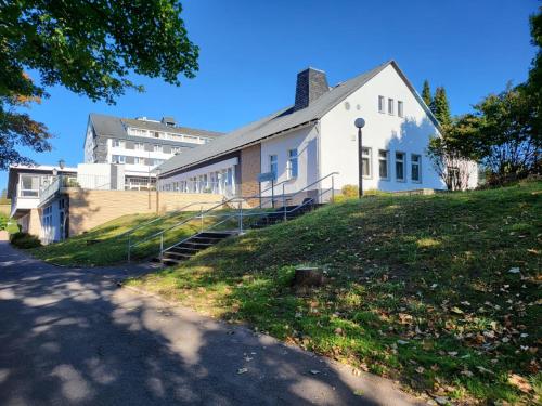 een wit gebouw bovenop een grasheuvel bij Werrapark Resort Hotel Frankenblick in Masserberg