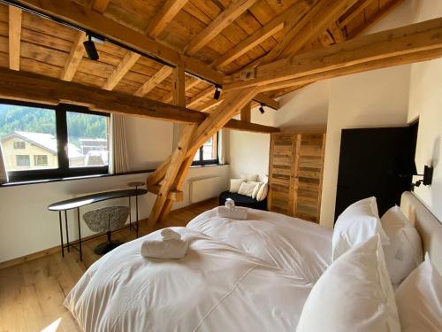 1 cama blanca grande en una habitación con techos de madera. en Le Marti, en Chamonix-Mont-Blanc