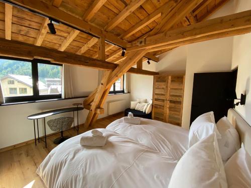 Cette chambre dispose d'un grand lit blanc et de plafonds en bois. dans l'établissement Le Marti, à Chamonix-Mont-Blanc