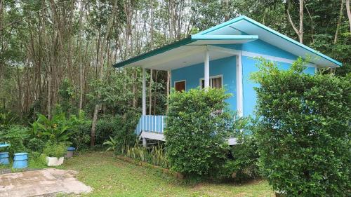 uma casa azul com um banco numa floresta em Baan seefa homestay kohyaoyai em Ko Yao Yai