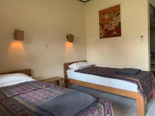 Habitación con 2 camas y una foto en la pared. en Prambanan Guesthouse en Yogyakarta