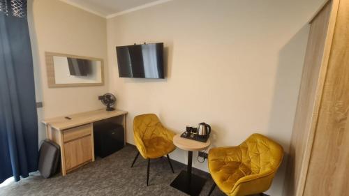 um quarto de hotel com duas cadeiras amarelas e uma secretária em Leśne Niebo em Lubniewice