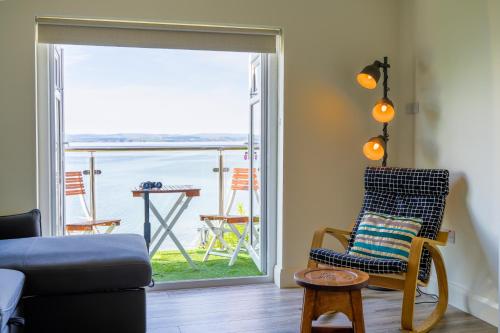 a living room with a chair and a view of the ocean at The Gaslight Inn Self Catering Holiday Apartments Rossnowlagh Donegal in Rossnowlagh