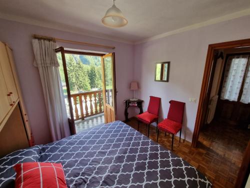 a bedroom with a bed and two red chairs at CASA NONNA RINA in Alagna Valsesia