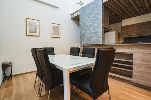 a dining room with a white table and black chairs at マークヴィラ諏訪湖 siteB in Shimo-suwa