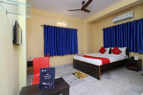 um quarto com uma cama e uma cadeira vermelha em OYO Maa Tara Guest House Near Acropolis Mall em Jādabpur