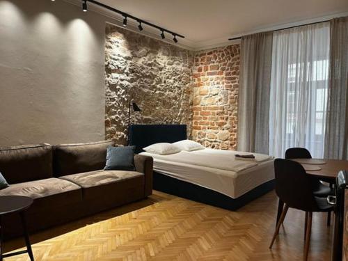 a bedroom with a bed and a couch and a brick wall at Apartamenty Rynek 5 in Lublin
