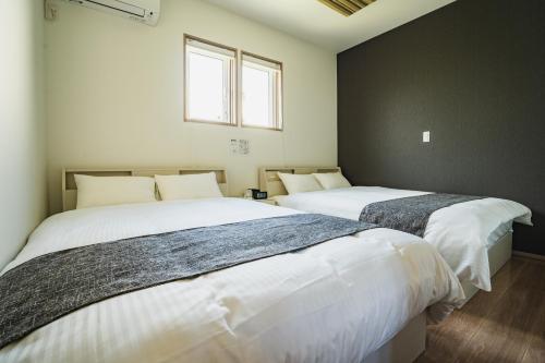 two beds in a room with two windows at マークヴィラ諏訪湖 siteB in Shimo-suwa