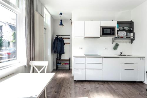a white kitchen with white cabinets and a window at Studio en deluxe appartement Blueberry in Zandvoort