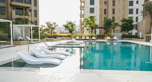a swimming pool with white chairs and buildings at Madinat Jumeirah Living in Dubai