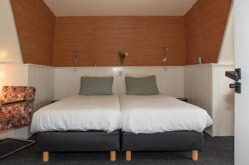 um quarto com 2 camas com lençóis brancos e almofadas verdes em Hotelhuisjes Aartswoud em Aartswoud