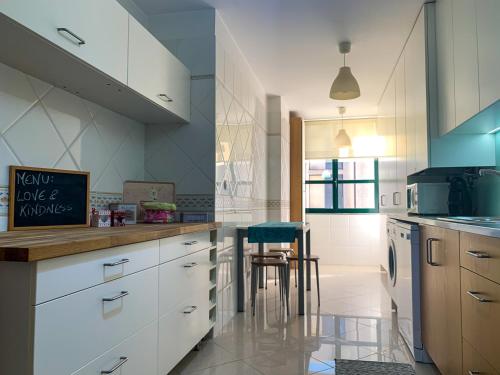 a kitchen with white cabinets and a table in it at Viana do Castelo, Cabedelo Beach Apartment in Viana do Castelo