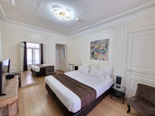 a bedroom with a large white bed and a couch at Hôtel Océanic - Grands Magasins in Paris