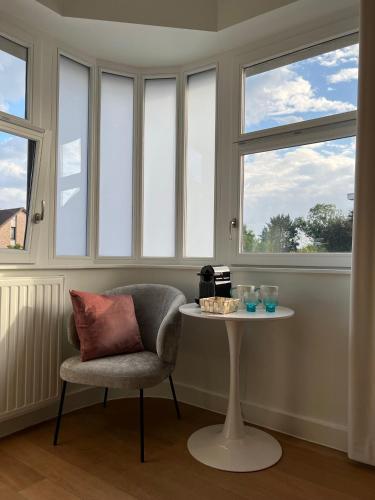 a table and a chair in a room with windows at Tuss in Kortrijk