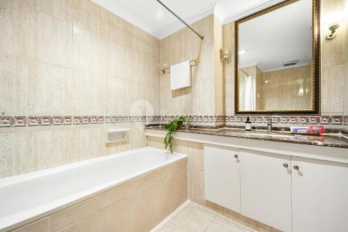 ein Badezimmer mit einer Badewanne, einem Waschbecken und einem Spiegel in der Unterkunft VIVEKA by Kozystay - SCBD in Jakarta