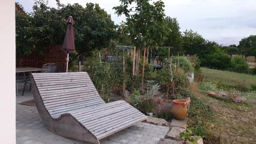a wooden bench and an umbrella in a garden at The view in Ilsfeld