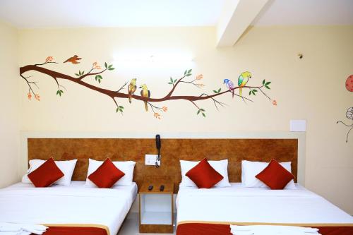 a bedroom with two beds with birds on a branch at Sasthi Suites in Bengaluru