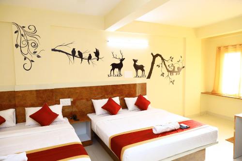 two beds in a hotel room with animals on the wall at Sasthi Suites in Bangalore