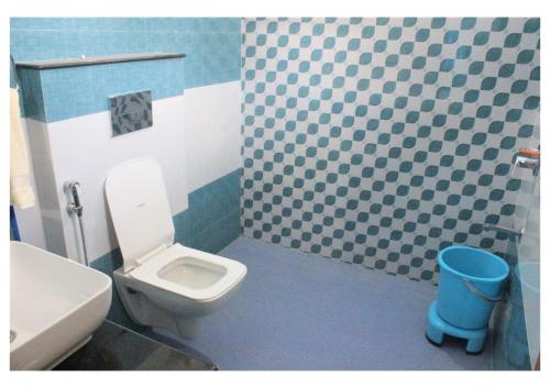 a bathroom with a toilet and a blue and white tiled wall at Kishkindha Wild 3BHK in Rāmnagar