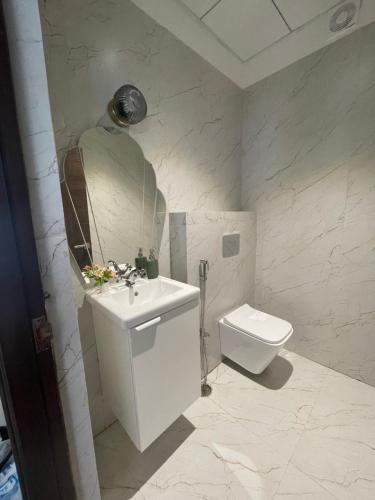 a white bathroom with a sink and a toilet at Bridge Service Apartment in Hyderabad