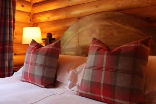 a bedroom with a bed with red and white pillows at Bunnahahbain - Two Bedroom Luxury Log Cabin with Private Hot Tub in Berwick-Upon-Tweed