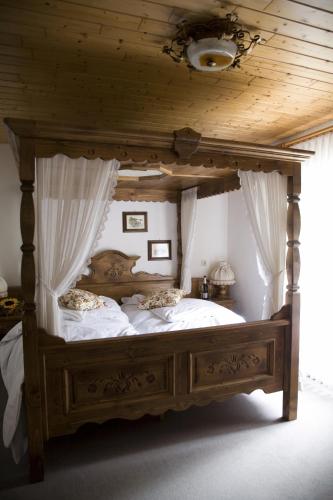 a canopy bed with white sheets and pillows on it at Landhotel am Wenzelbach in Prüm