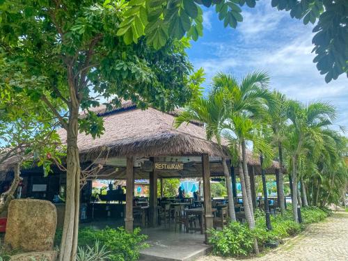 a restaurant with palm trees in front of it at Long Hải Channel Beach Resort in Long Hai