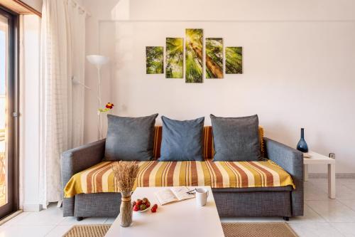 a living room with a couch with three paintings on the wall at ALTIDO Deluxe apt with terrace in Costa da Caprica in Costa da Caparica
