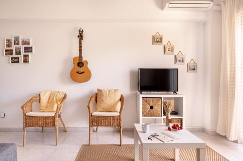 a living room with a table and chairs and a guitar on the wall at ALTIDO Deluxe apt with terrace in Costa da Caprica in Costa da Caparica