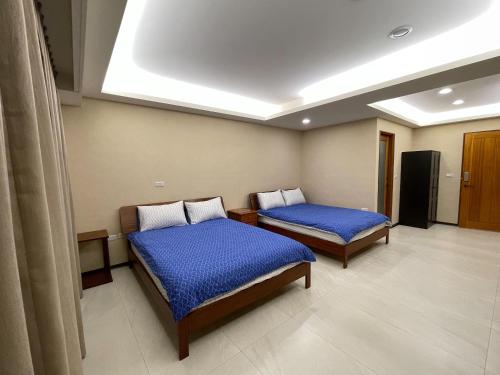 台南的住宿－新興九洲會館 ，一间医院房间,配有两张带蓝色床单的床