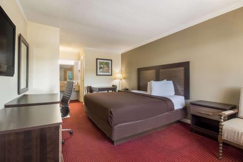 a hotel room with a bed and a flat screen tv at Suburban Studios Florence I-95 in Florence