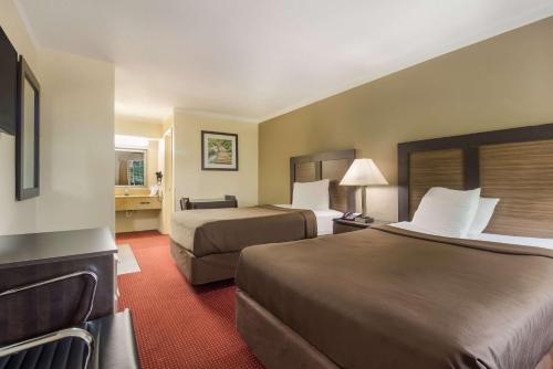 a hotel room with two beds and a bathroom at Suburban Studios Florence I-95 in Florence