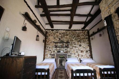 Habitación con 4 mesas y una pared de piedra. en Hotel Nasho Vruho, en Berat