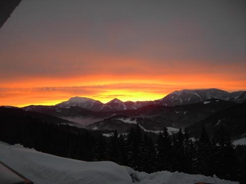 a sunset over a mountain range with snow and trees at Höhenstein in Lunz am See