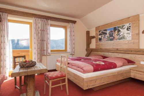 a bedroom with a bed and a table and two windows at Höhenstein in Lunz am See