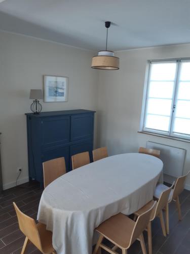 une salle à manger avec une table et des chaises blanches dans l'établissement Maison de vacances-La balade des deux Caps, à Audinghen