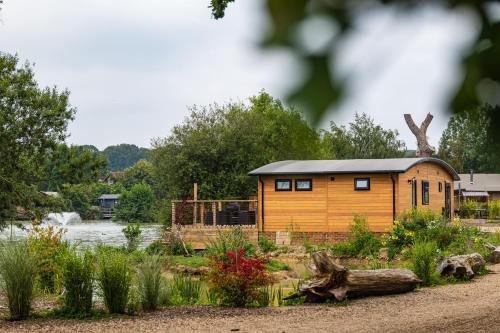 a cabin in a garden next to a river at Sumners Ponds Fishery & Campsite in Horsham