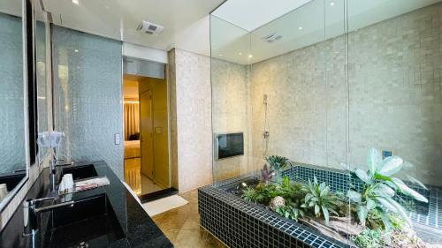 łazienka z prysznicem i umywalką z roślinami w obiekcie Janeeyre Motel w mieście Taizhong