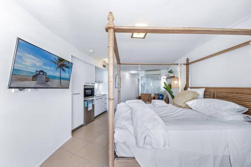 Three A Airlie Seaviews, Pool, Private Spa في شاطئ إيرلي: غرفة نوم مع سرير مغطى وتلفزيون على الحائط