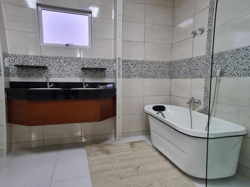 a bathroom with a tub and a sink and a tv at Pousada Caminhos da Vila Chantal in Campos do Jordão