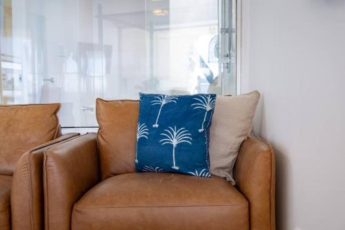 a brown couch with a blue pillow on it at Three A Airlie Seaviews, Pool, Private Spa in Airlie Beach