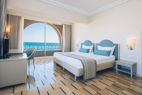 a hotel room with a bed and a large window at Iberostar Averroes in Hammamet