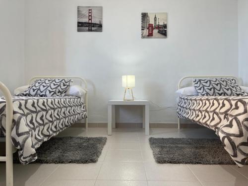 Zimmer mit 2 Betten und einem Tisch mit einer Lampe in der Unterkunft Low Island House in Los Silos