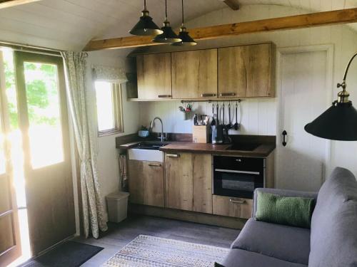 uma cozinha com armários de madeira e um sofá num quarto em The Hut in the Orchard @ Yorecroft em Aysgarth