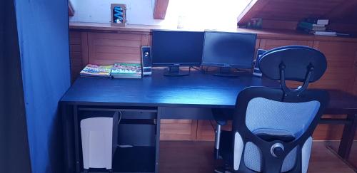 a desk with two computer monitors and a chair at Schöne Wohnung mit Balkon Non-Smoking in Klosterlechfeld