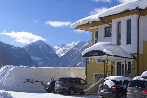 a snow covered building with cars parked in a parking lot at Villa Castelli in Schladming