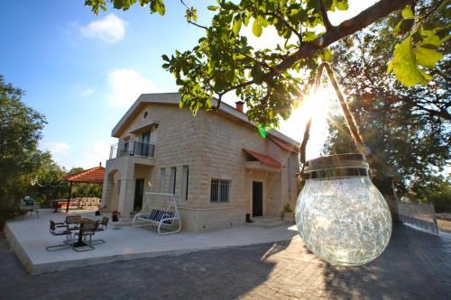 a large glass jar hanging from a tree in front of a house at Beit Mema in Aḑ Ḑahr