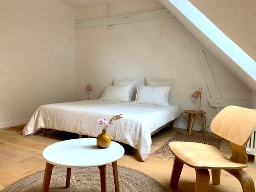 a bedroom with a bed and a table and chairs at La Maison Vivante, chambres d'hotes au coeur du Perche in Les Étilleux