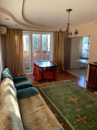 ein Wohnzimmer mit einem Sofa und einem Tisch in der Unterkunft Квартира трехкомнатная in Almaty