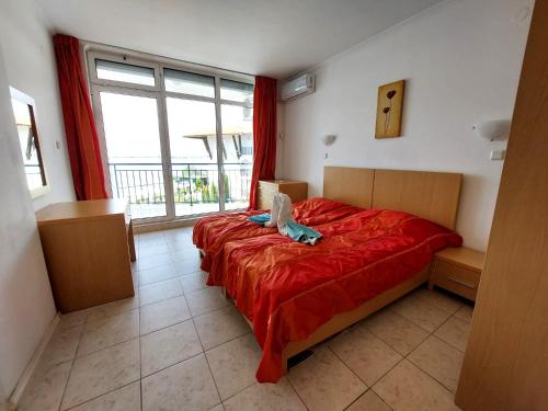a bedroom with a red bed and a window at Vega Village Ap B39 in Sveti Vlas